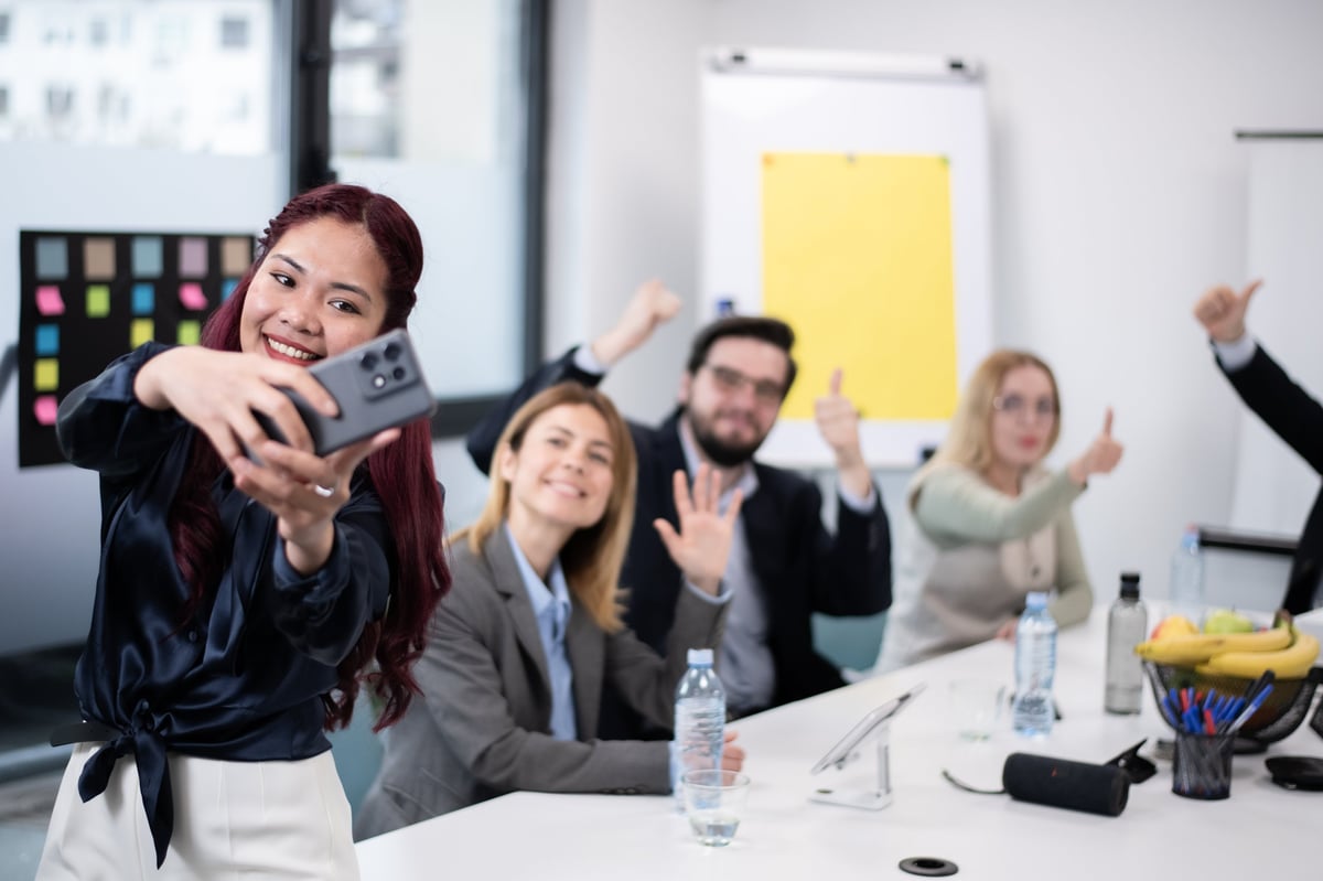 Team of colleagues smiling and posing for a group selfie photo