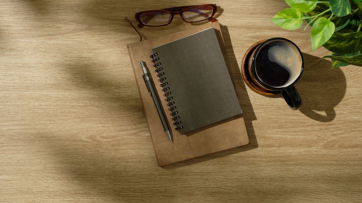 Flat lay of cozy workspace with coffee, notebook, and plant